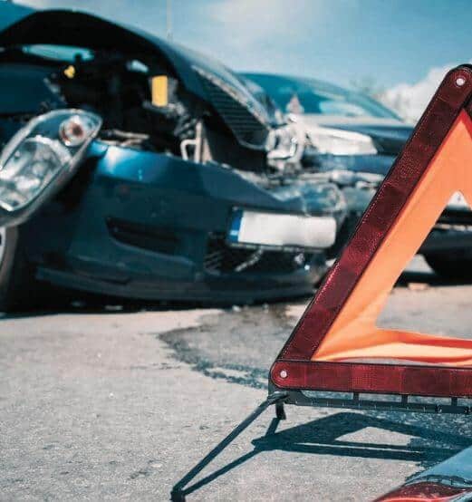 Damaged cars behind a red warning triangle after a collision