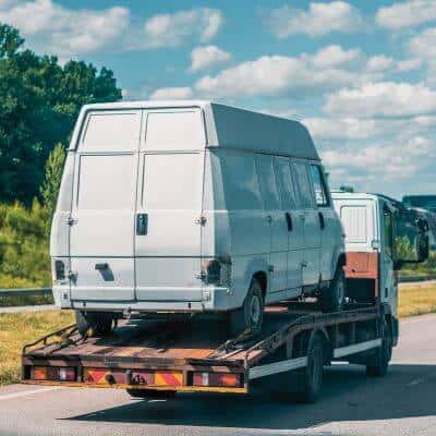 Flatbed truck hauling a white cargo van